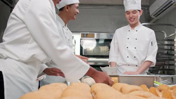 Chefs team in uniforms prepare to bake bread and pastry in stainless kitchen.