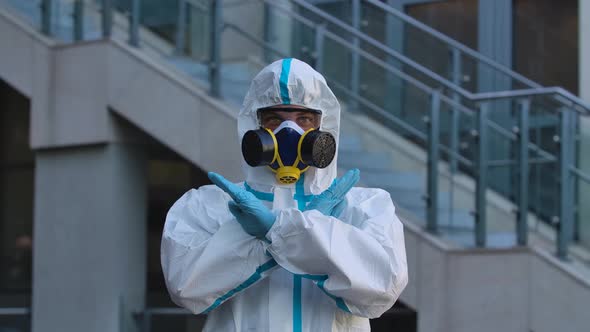 Portrait of a Young Man in a Protective Suit, Respirator, Gloves and Safety Glasses Looks Into the