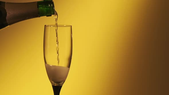 Pouring Champagne Over Golden Background. Pouring Champagne Wine Into Glass