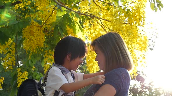 Asian Mother Holding Her Son While Walking In The Park , Back To School Concept Slow Motion