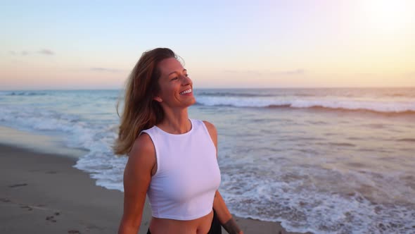 Happy and playful woman at the beach at sunset