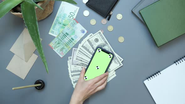 Smartphone with green screen chroma key and cash money lying on office table