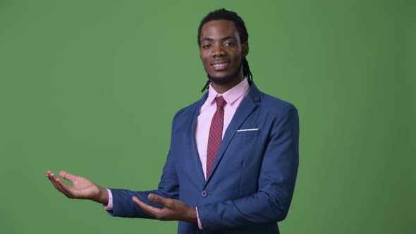 Young Handsome African Businessman with Dreadlocks Against Green Background