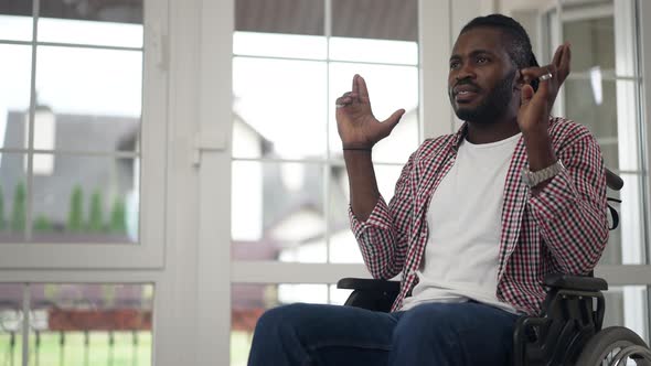 Portrait of Hoping African American Disabled Man in Wheelchair Wishing with Fingers Crossed