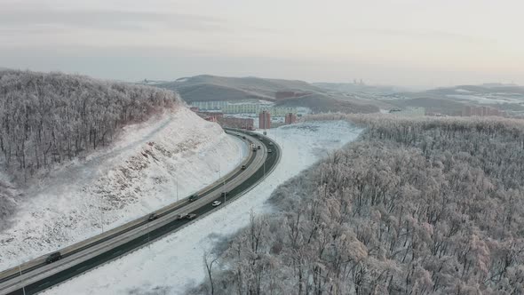 Flight of the Drone From the Road with Traffic Among the Mountains in Winter