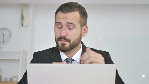 Tired Businessman Rubbing Eyes While Working on Laptop