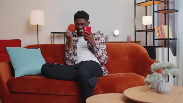 Man Sitting at Home Using Credit Bank Card and Smartphone While Transferring Money Online Shopping