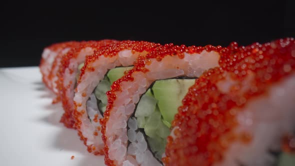 California Sushi Roll with Rice Salmon Avocado Cucumber and Caviar on a White Plate on a Black