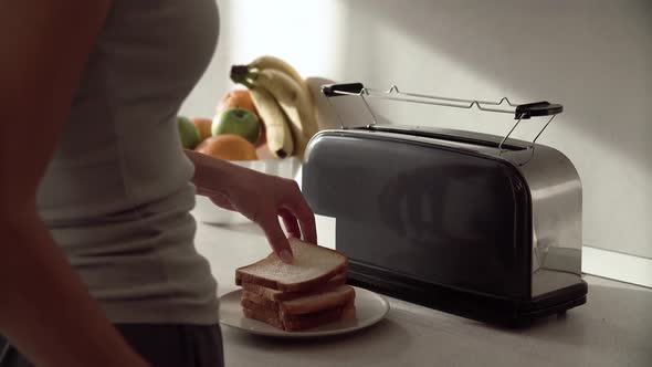 Breakfast. Woman Putting Slicing Bread In Toaster Closeup