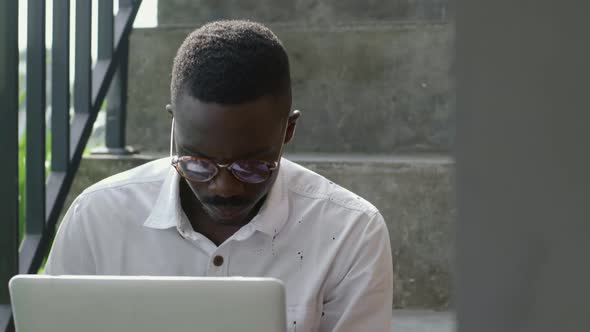 Man Sitting on Stairs and Working