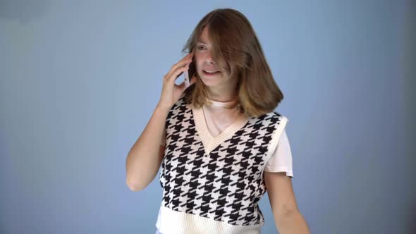 teenage girl talking excitedly on the phone on blue background