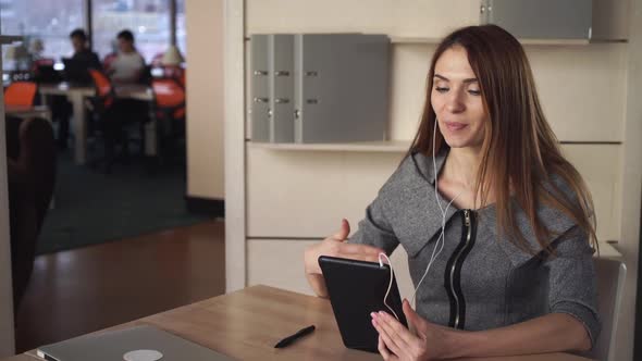 Attractive Businesswoman Using App on the Touch Screen Tablet for Video Call.