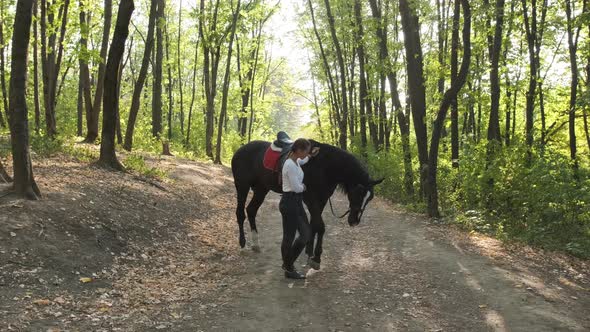 The Young Woman Gently Strokes Her Horse in the Park, While Trying To Train Him