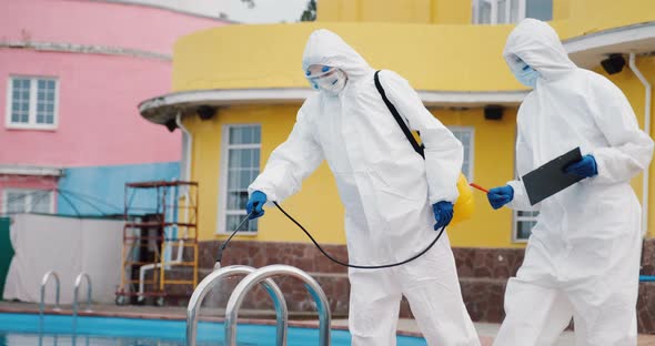 Two doctors team in protective suits disinfect swimming pool, control sanitation	