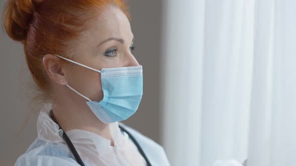 Side View Closeup Face of Frustrated Tired Caucasian Redhead Woman in Covid Face Mask Looking Out