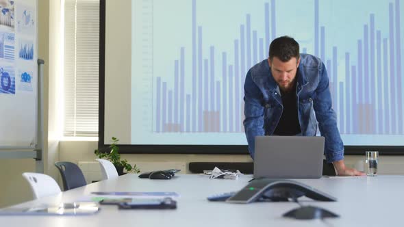 Front view of young caucasian businessman working on laptop in modern office 4k