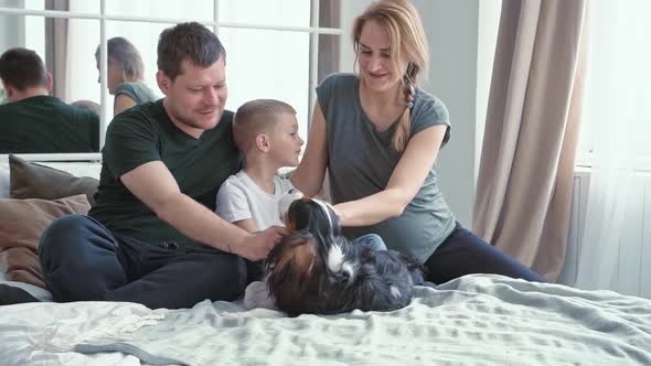 Loving Family and Little Son a Boy of European Appearance Sitting on a Bed in a Cozy Modern Room