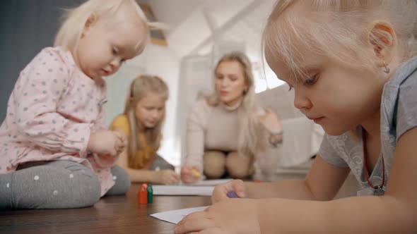 Three Girls and Babysitter Drawing on Floor of Cozy Apartment.