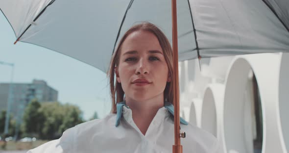 Attractive caucasian woman holding an umbrella with confident look to the camera