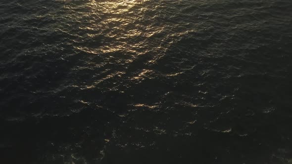 Aerial view of waves breaking on shore. TILT UP to reveal deep blue water of the Mediterranean Sea w