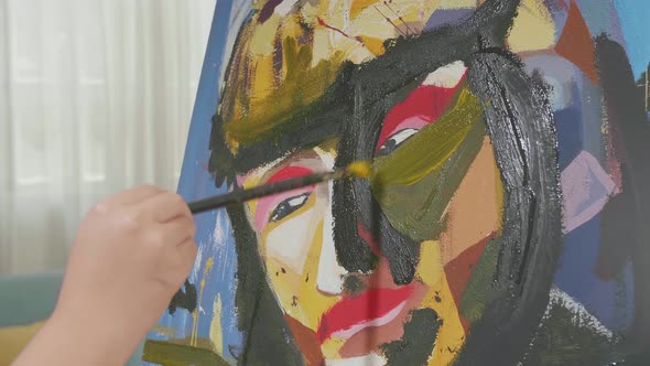 Close Up Of A Hand's Girl Holding Paintbrush And Painting A Girl's Face On The Canvas