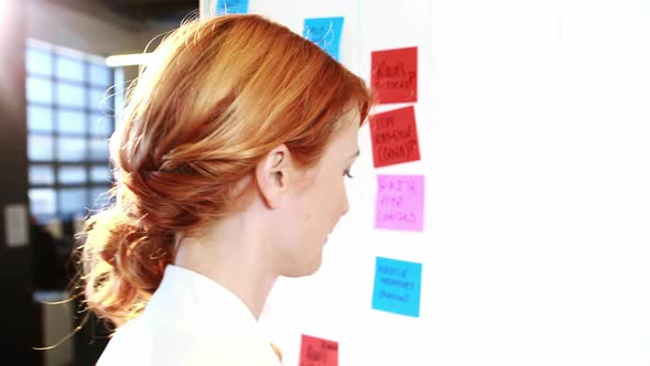 Woman putting sticky notes on whiteboard