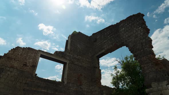 Ruined Wall on a Background of White Moving Clouds. Blue Sky. Brick Walls