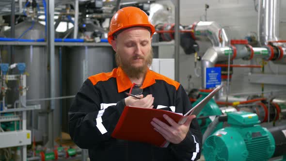 An Industrial Operator at a Manufacturing Plant Inspects the Equipment and Transmits Readings Via