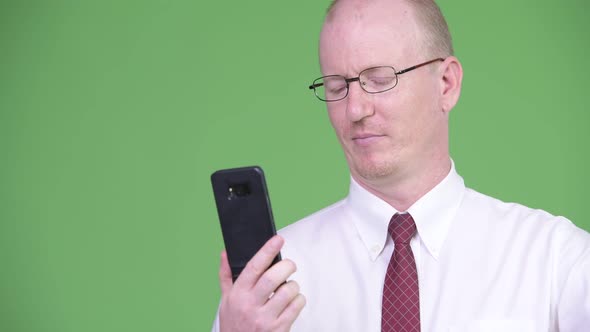 Happy Mature Bald Businessman Smiling While Using Phone