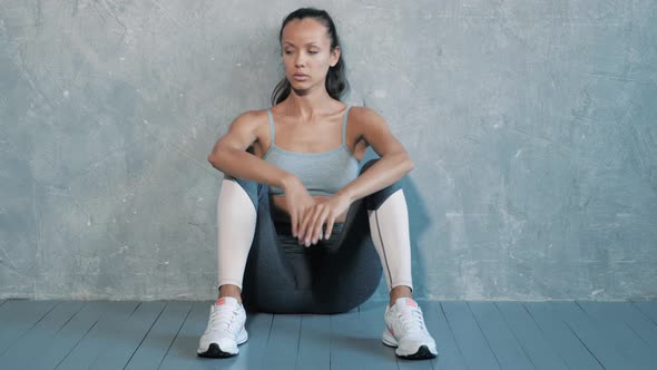 Pretty woman wearing sportswear.Beautiful girl sitting after training in studio