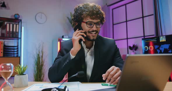 Businessman in Formal Stylish Wear Enjoying Phone Conversation During his Work on Laptop