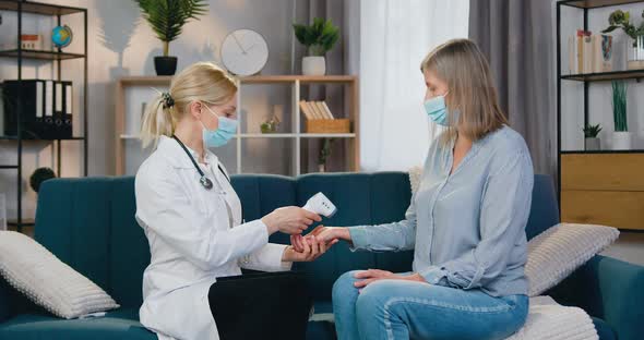 Doctor Measuring Body Temperature on Wrist of Female Patient Using Digital Scan Thermometer