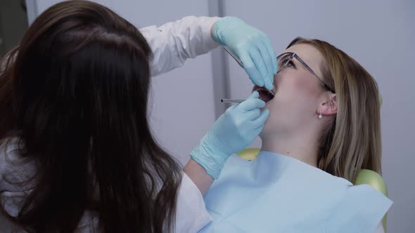 Female Dentist in Medical Gloves Using Tools for Working with Patient in Clinic