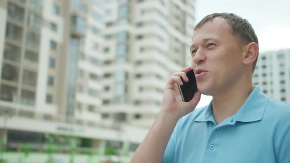 Portrait of a Young Man Talking on a Mobile Phone While Standing on a City Street