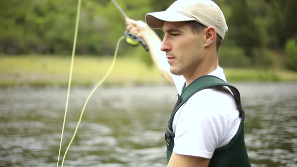 Slow Motion Shot of a Caucasian man casting his hook while Fly Fishing. He is standing in the middle