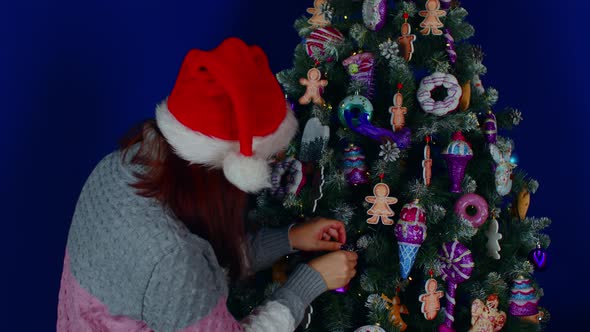 Side View of Woman in Santa Hat Decorating Christmas Tree