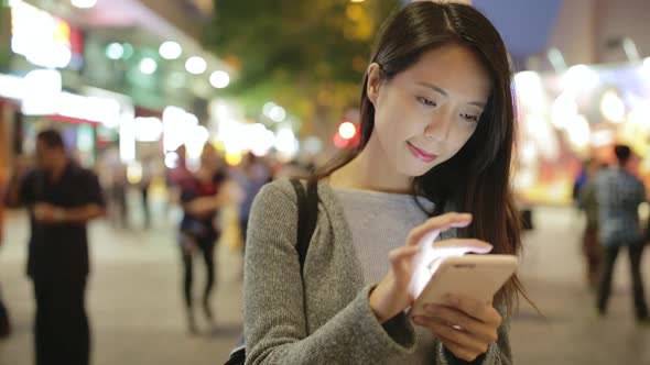 Woman use of smart phone at night in Hong Kong