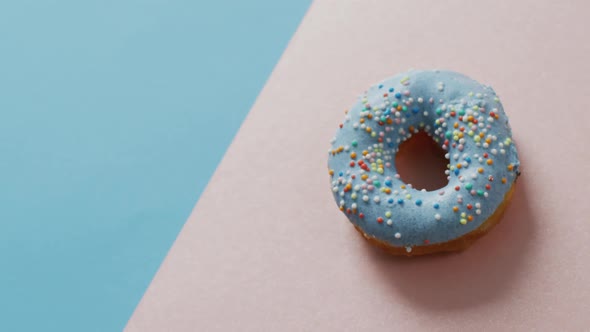 Video of donut with icing on blue and pink background