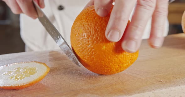 Close up of a chef knife peeling and slicing an orange