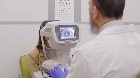 Professional Optometrist Examining Eye of Woman with Autorefractor