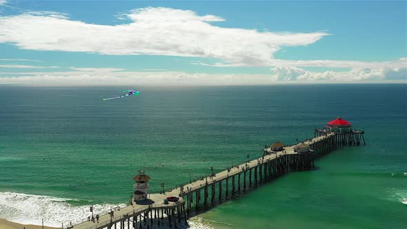 Drone footage of a kite flying over the Huntington Beach pier.