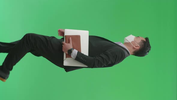 Asian Business Man Holding Book And Document While Walking On Green Screen, Wear Medical Mask