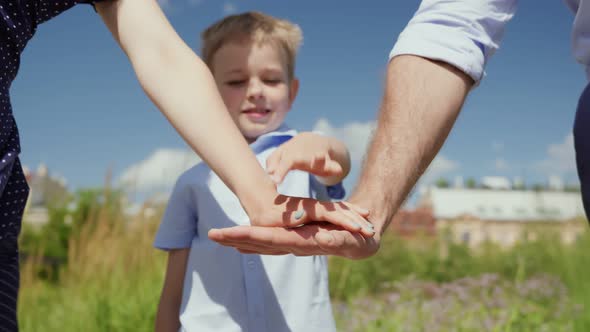 Cropped Shot of Mother Father and Preschool Son Put Hands Together Outdoors