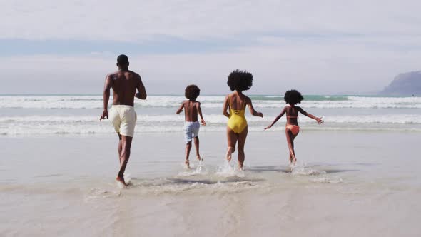 African american parents and two children running at the beach