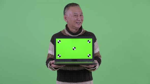 Happy Mature Japanese Man Thinking While Showing Laptop and Talking