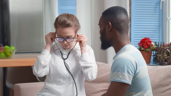Young Doctor Examining Patient with Stethoscope at Home