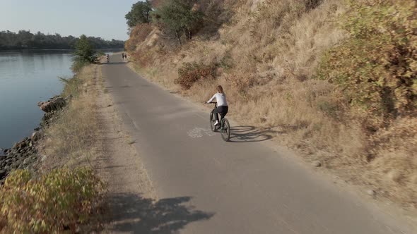 The Beautiful Lady Ride on the Bike Along a River