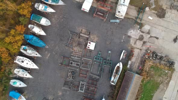 Small shipyard with boat parts and finished boats, aerial top down view