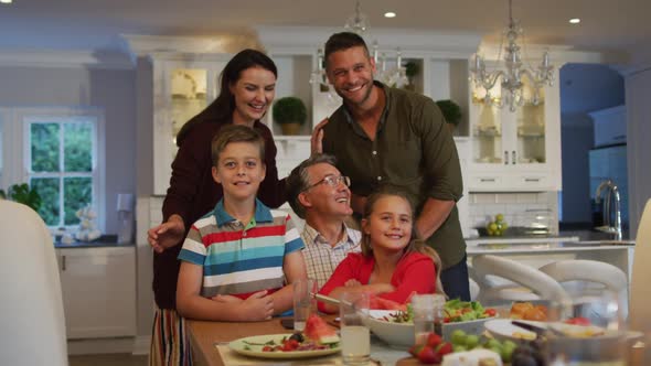 Portrait of caucasian parents, son, daughter and grandfather sitting at table after family meal