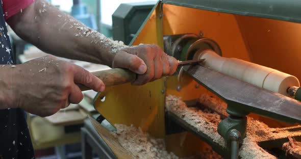 Woodworker carving a wooden bowl. Joinery. Carpenter with a cutter works on a wooden lathe